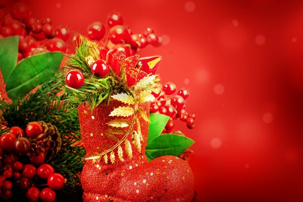 Красный сапожек с новогодними украшениями на красном фоне в тематику рождества