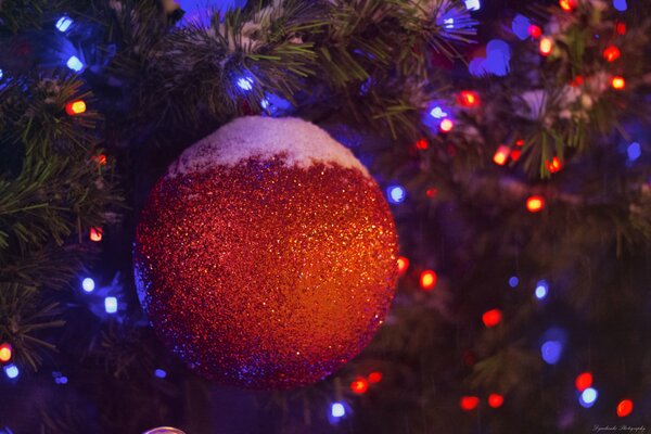 Bola roja de Navidad con nieve en el árbol de Navidad