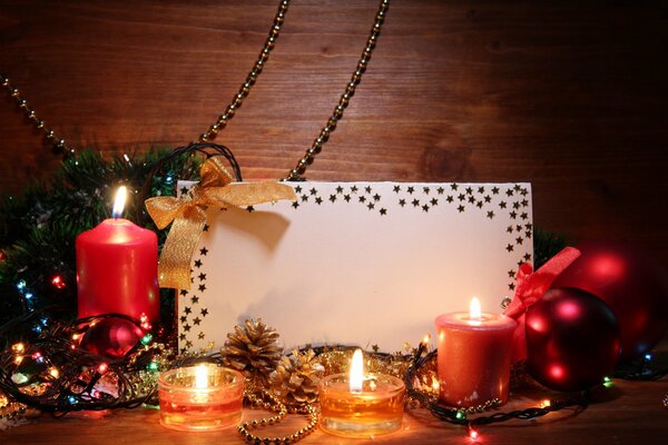 Velas, adornos de árbol de Navidad y una tarjeta en la mesa