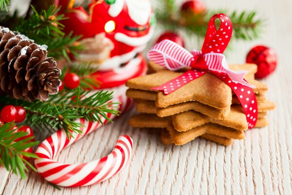Pasteles de año nuevo y piruletas bajo el árbol de Navidad con un cono de pino