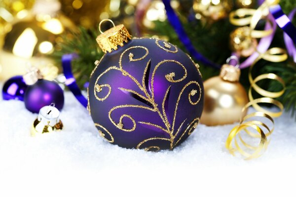 Purple New Year s ball in the snow under a fir branch