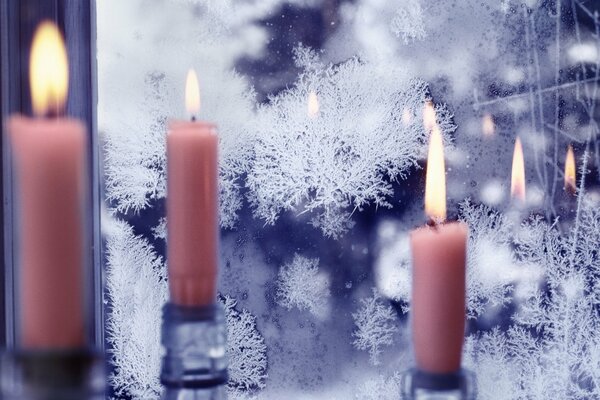 Burning candles on the background of a winter window