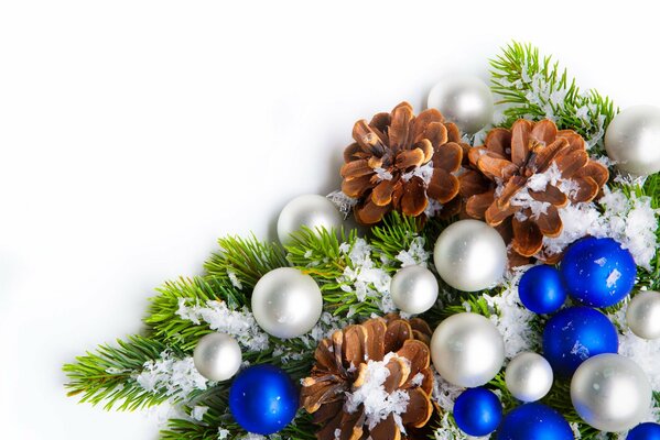 A branch of a Christmas tree with toys and cones in the snow