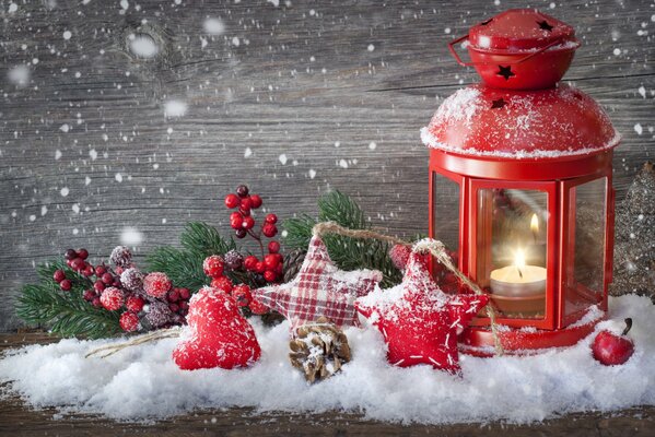 Candelabro de linterna roja en la nieve entre los juguetes del árbol de Navidad