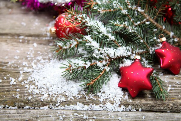 Christmas tree toys and fir branches on a wooden table in the snow