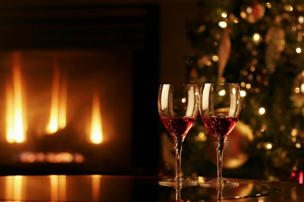 Fuego festivo en la chimenea. Copas de vino y árbol de Navidad