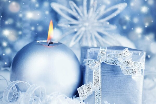 Płonąca świeca i prezent na płatkach śniegu