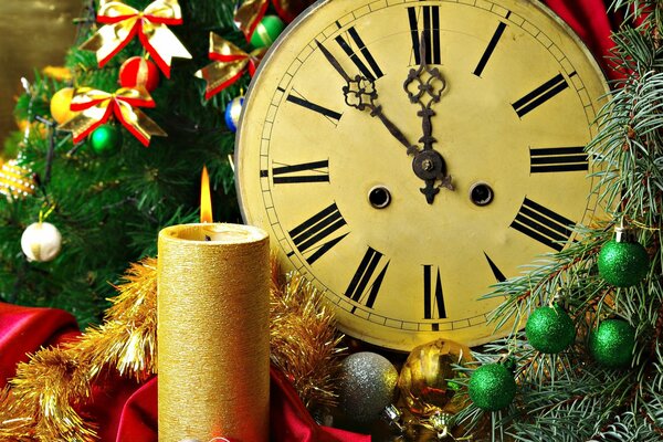 Bougie et horloge du nouvel an dans la décoration du nouvel an à partir de branches de sapin dans des arcs et des boules multicolores