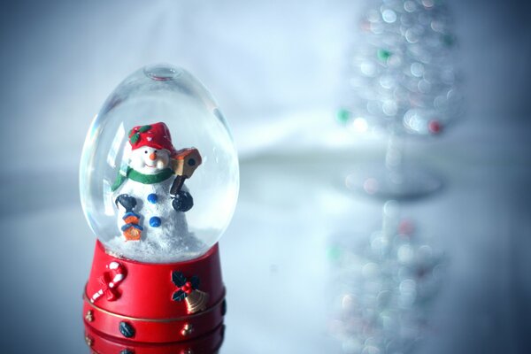 Bola de cristal del muñeco de nieve en la mesa de cristal