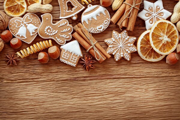 Рождественское печенье с белой глазурью, палочки корицы и сушеные апельсины на деревянном столе