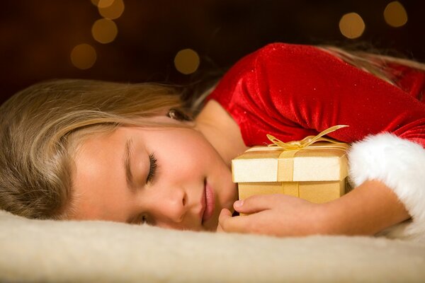 Niña dormida abrazando un regalo