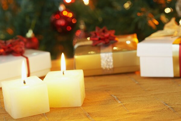 Burning little candles at gifts under the Christmas tree