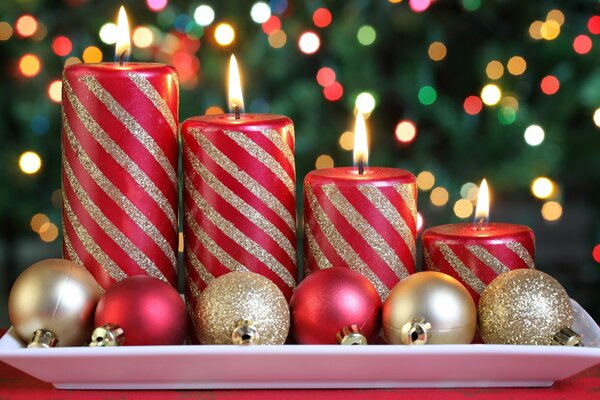 A set of red candles with gold stripes is in a plate