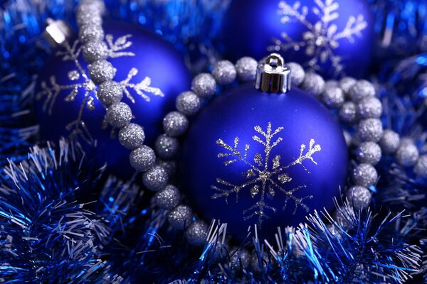 Bolas azules de Navidad decoradas con copos de nieve plateados en oropel azul
