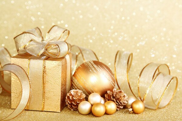 Gift box and golden balls on a golden background