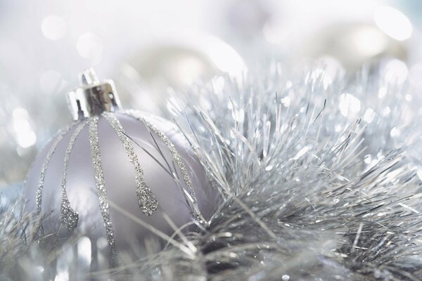 A ball on fluffy tinsel is showered with silver