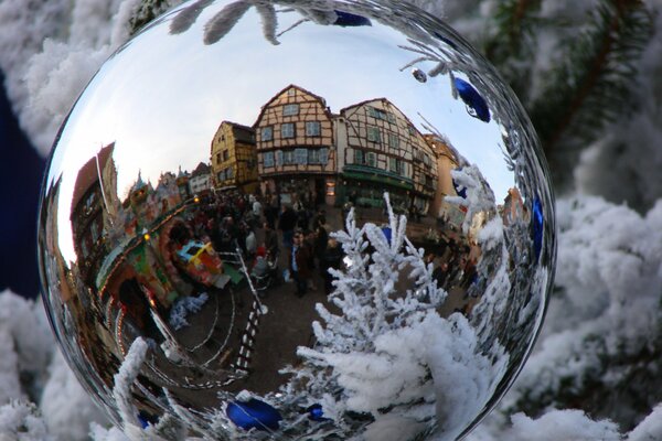 Riflesso di una bella città in una palla di Capodanno su un albero di Natale innevato