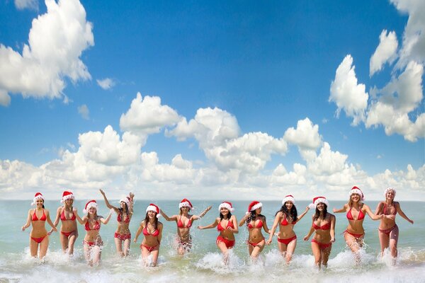 Girls in bikinis in the ocean in santa hats
