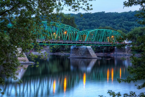 Puente verde en luces en el río