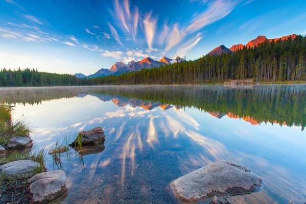 La superficie del lago refleja las montañas y las nubes del atardecer