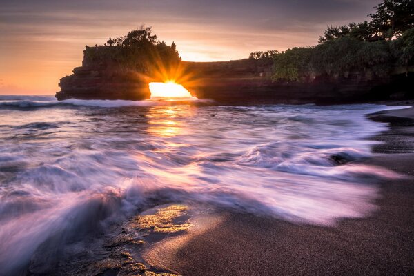 The rays of the sun through the rock on the shore