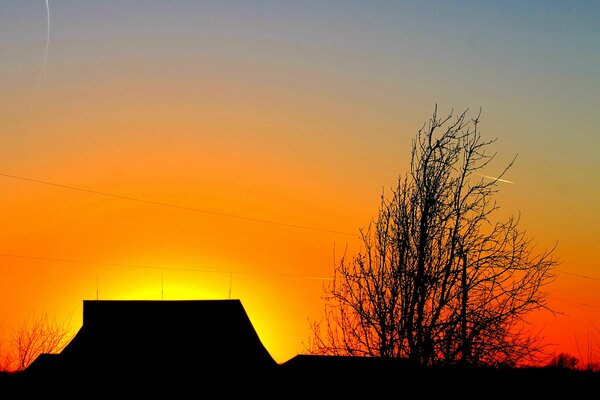 Above the house, the sky is decorated with a red sunset