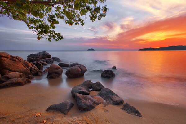 Красивый закат на берегу с камнями