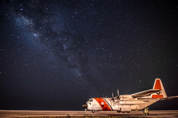 Avión de transporte militar Hércules en el aeródromo contra el cielo nocturno estrellado