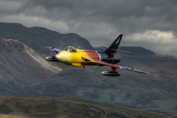 El avión hawker hunter vuela cerca de las montañas