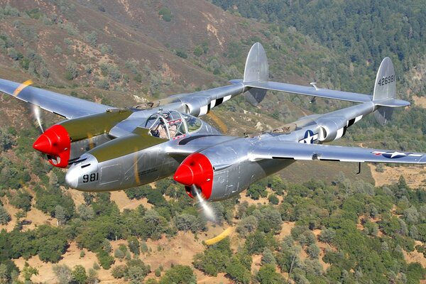 An old plane flies over the hills