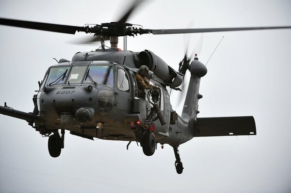 Ein Soldat mit einem Maschinengewehr fliegt in einem Militärhubschrauber