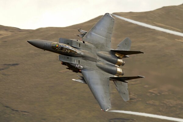 An f15 military plane flies over the desert