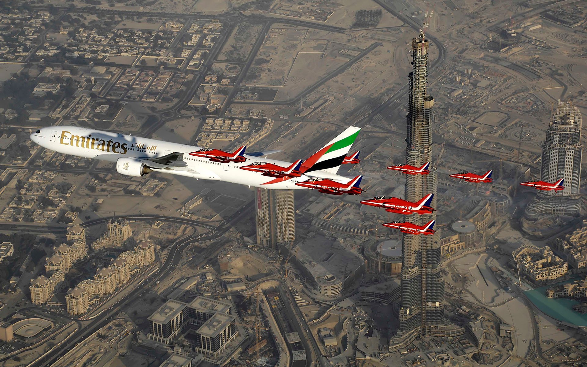 airplane passenger airliner boeing 777 airline emirates family wide-body passenger aircraft for airlines large length in sky over dubai escorted by royal air force forces hawker siddeley hawk british