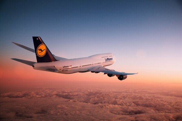 A plane in the air at sunset over the mountains