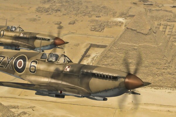 Spitfire plane in the desert on the background of pyramids