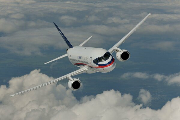 The Sukhoi Superjet 100 aircraft flies against the background of clouds