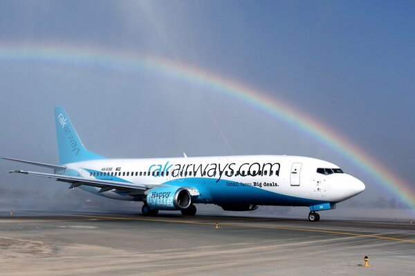 Immagine di un Boeing in un aeroporto con un bellissimo arcobaleno