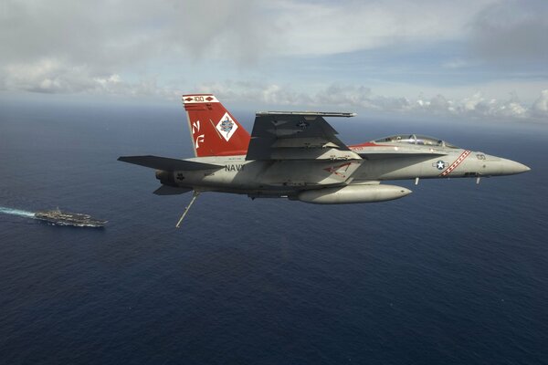 A fighter bomber flies over an aircraft carrier