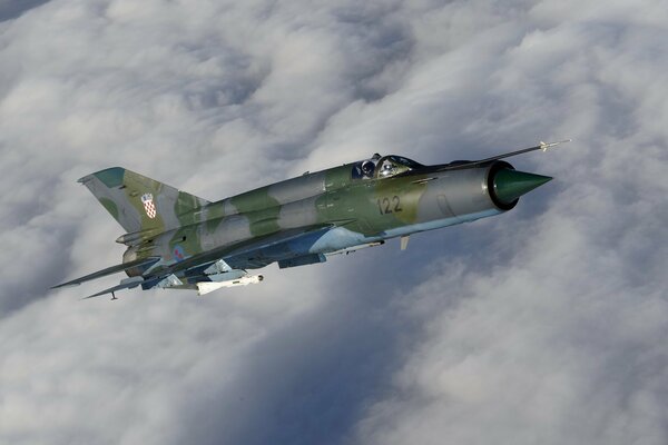 MIG-21 soviético en el cielo con nubes en el fondo