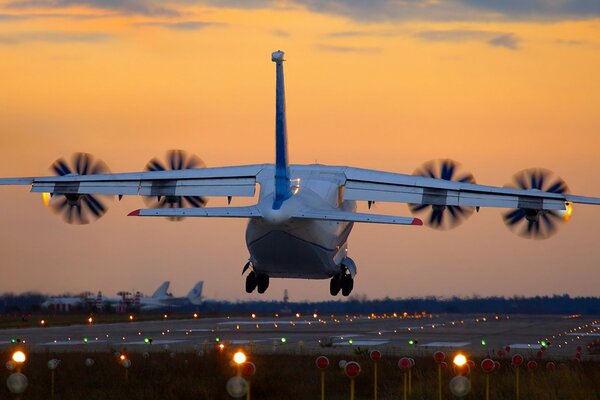 Ein Flugzeug bei Sonnenuntergang landen. Die Lichter der Landebahn leuchten