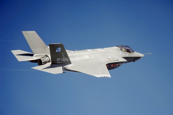 A grey fighter jet is flying across the blue sky