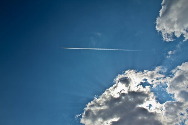 Eine Spur von einem Flugzeug in einem blauen Himmel mit Wolken