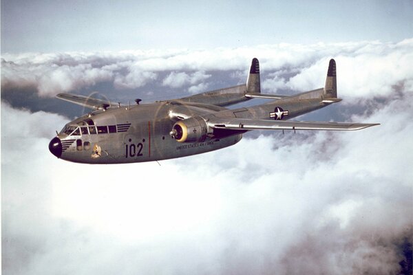 A military plane is flying in the clouds