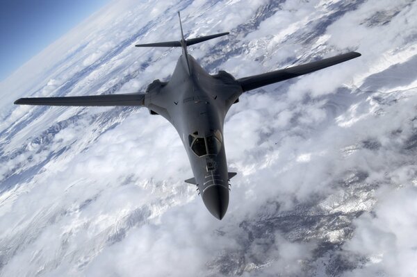 A gray plane is flying above the clouds