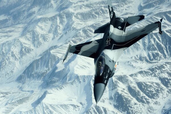Na śnieżnobiałym tle gór widać lot myśliwca