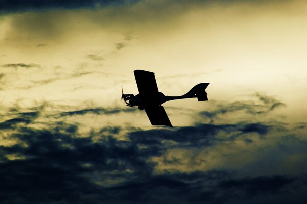 Ciemny samolot leci na tle ciemnych chmur