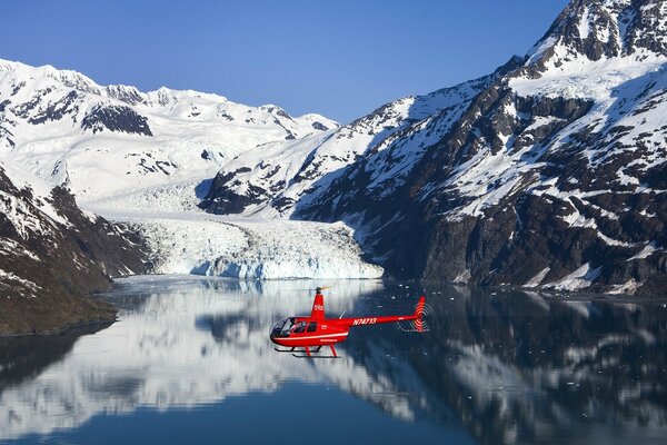 Roter Hubschrauber über einem See in den Bergen