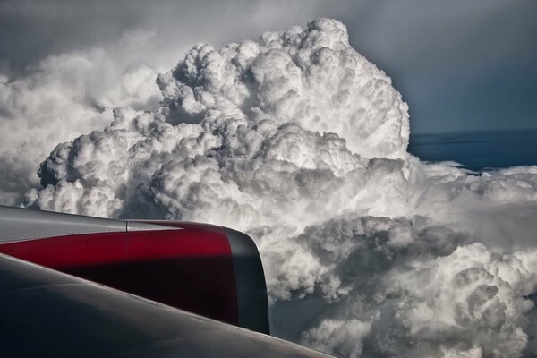 En el fondo de las nubes duras, el ala del avión es visible