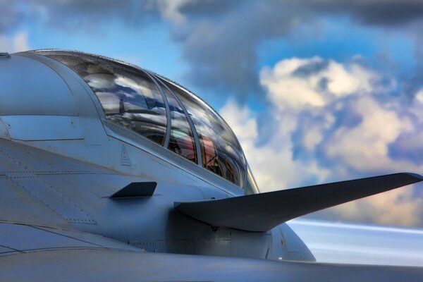 The cockpit of a fighter jet against the blue sky