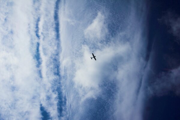 A small plane is flying against the background of a cloud